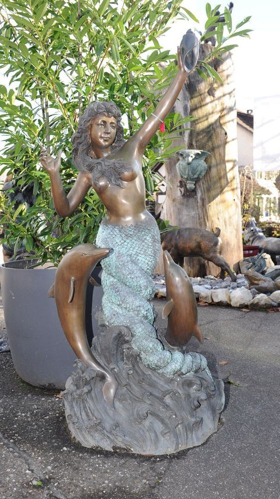 Meerjungfrau aus Bronze begleitet von springenden Delfinen