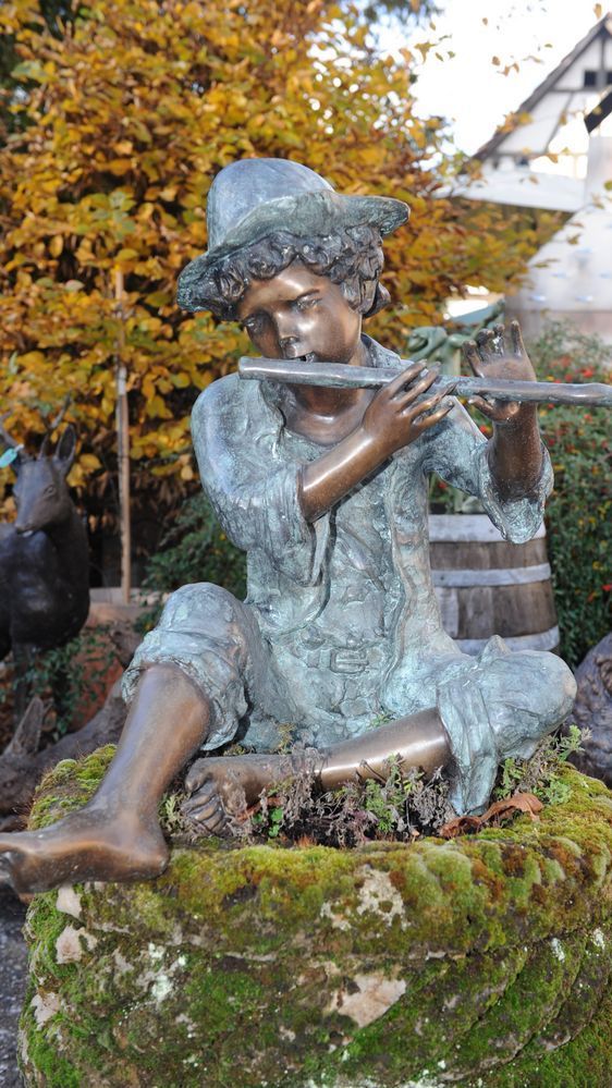 Sitzende Bronzefigur von flötenspielendem Jungen
