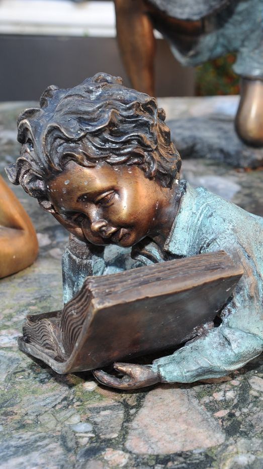 Liegende Bronzefigur von lesendem Jungen