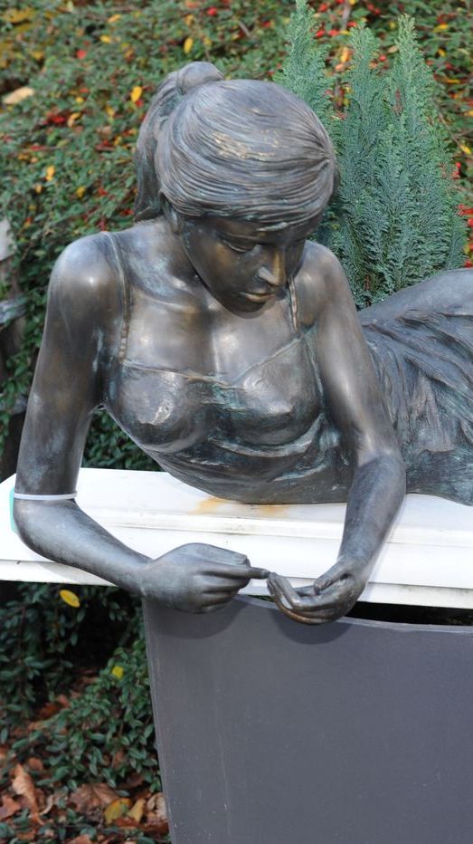 Bronzefigur von liegender Frau mit nachdenklichem Blick