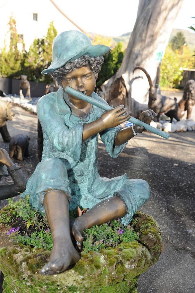 Bronzeskulptur eines Flötenspielers mit angezogenen Beinen