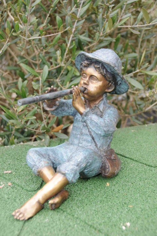 Sitzende Bronzefigur von sitzendem Flötenspieler mit Hut und Tasche